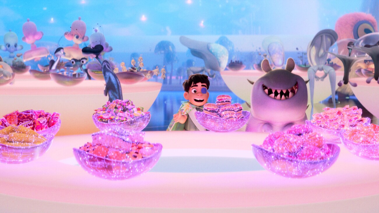 Elio and Glordon sat at a table full of sparkling food in a still from the Disney•Pixar movie "Elio."