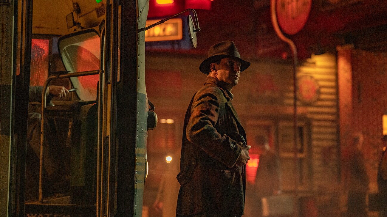 Bradley Cooper stands outside of a bus, from the 20th Century Studios movie, Nightmare Alley.