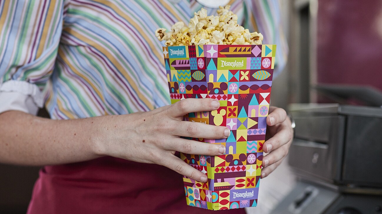 Image of a person holding a box of popcorn from Disneyland.