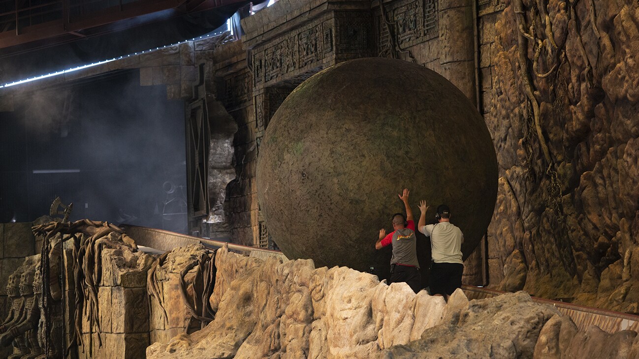 Image of two cast members rolling the giant ball from the Indiana Jones Adventure ride.
