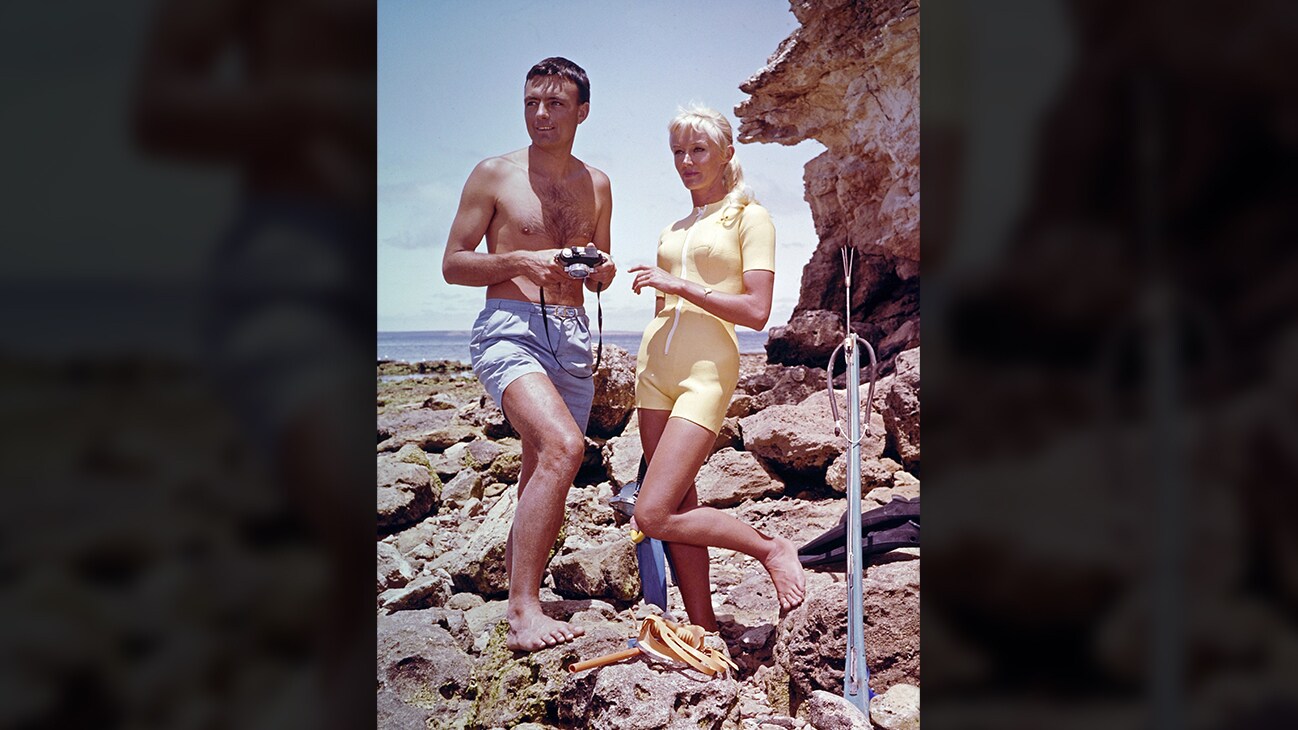 Ron & Valerie Taylor with spearfishing equipment standing on rocks in 1962. (photo credit: Ron & Valerie Taylor)