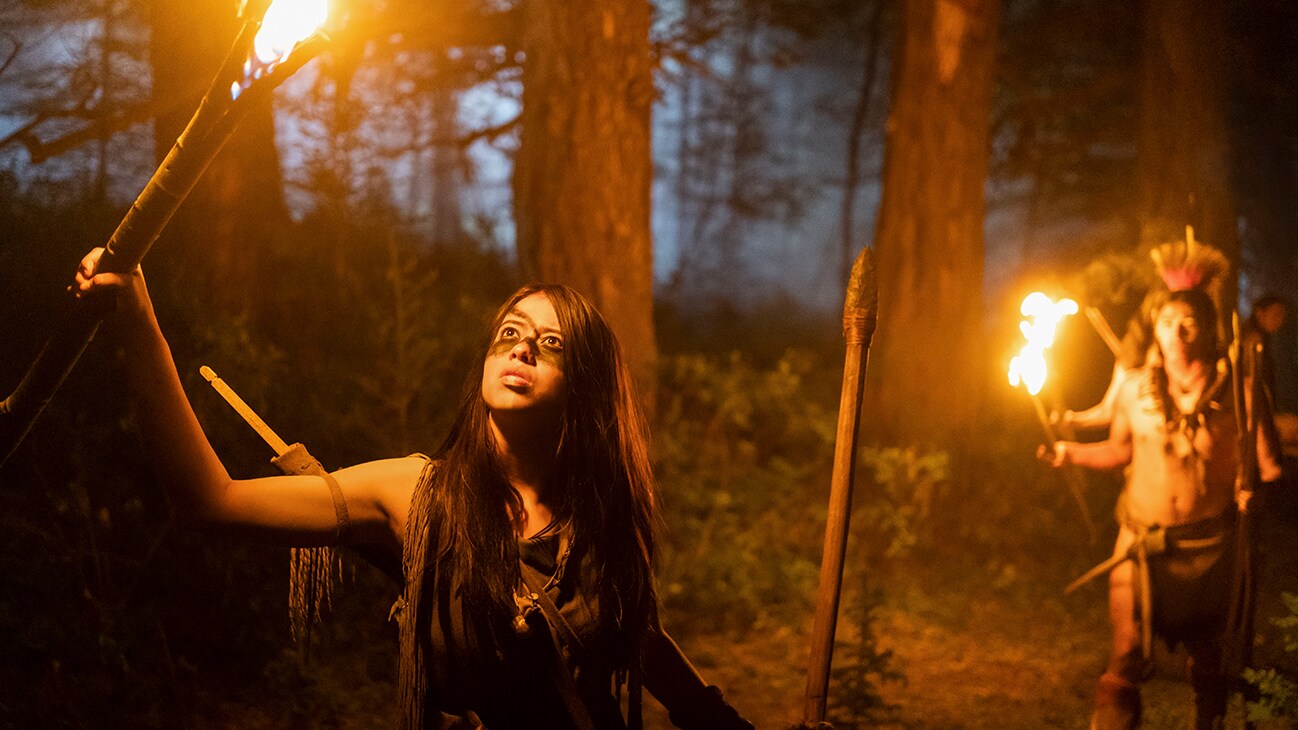 Naru (actor Amber Midthunder) holding a torch looking up from the Hulu original movie, "Prey".