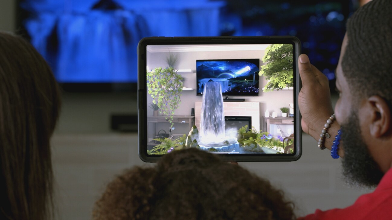 A tablet device in front of a TV showing a waterfall pouring out of the TV screen from the Disney+ AR short, "Remembering".