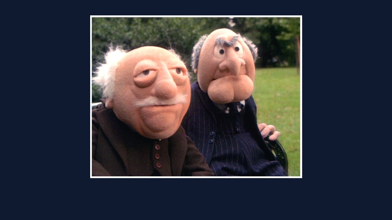 Statler and Waldorf sitting on a park bench from the Disney movie The Great Muppet Caper.