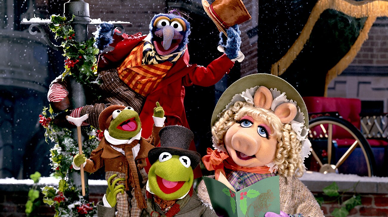 The Great Gonzo as Charles Dickens (voice of Dave Goelz), Kermit the Frog as Bob Cratchit (voice of Steve Whitmire), Tiny Tim Cratchit (voice of Jerry Nelson), and Miss Piggy as Emily Cratchit (voice of Frank Oz) in the Disney movie The Muppet Christmas Carol.