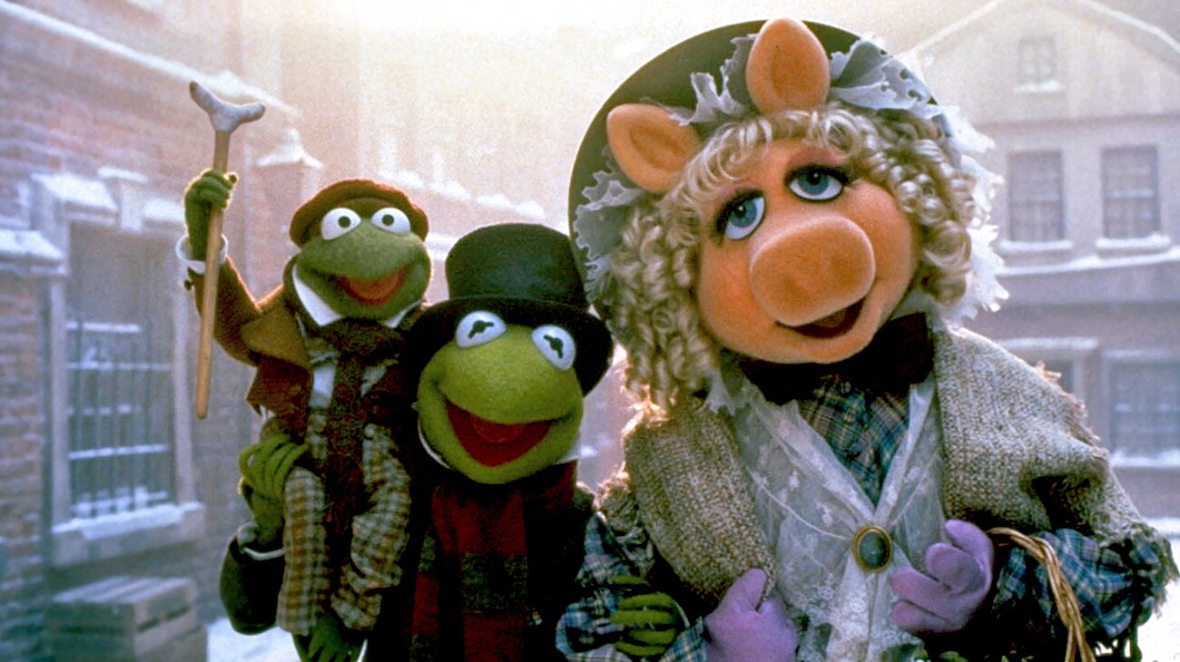 Kermit the Frog as Bob Cratchit (voice of Steve Whitmire), Tiny Tim Cratchit (voice of Jerry Nelson), and Miss Piggy as Emily Cratchit (voice of Frank Oz) in the Disney movie The Muppet Christmas Carol.