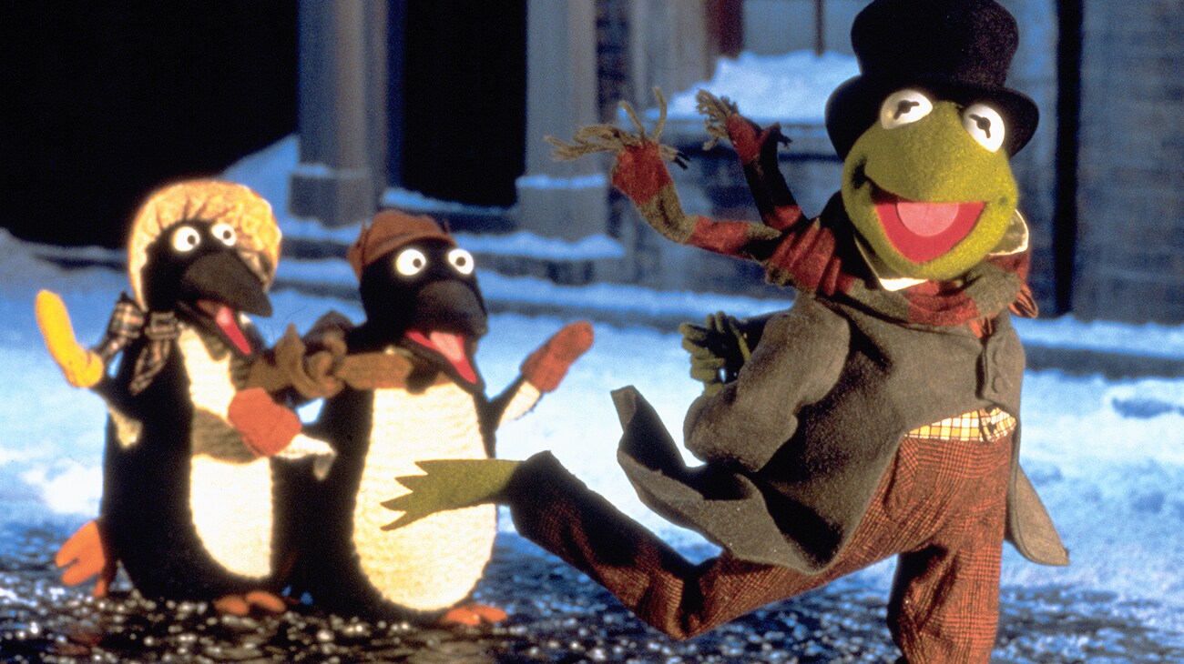 Kermit the Frog as Bob Cratchit (voice of Steve Whitmire) walking with penguins (voice of Jerry Nelson) from the Disney movie The Muppet Christmas Carol.