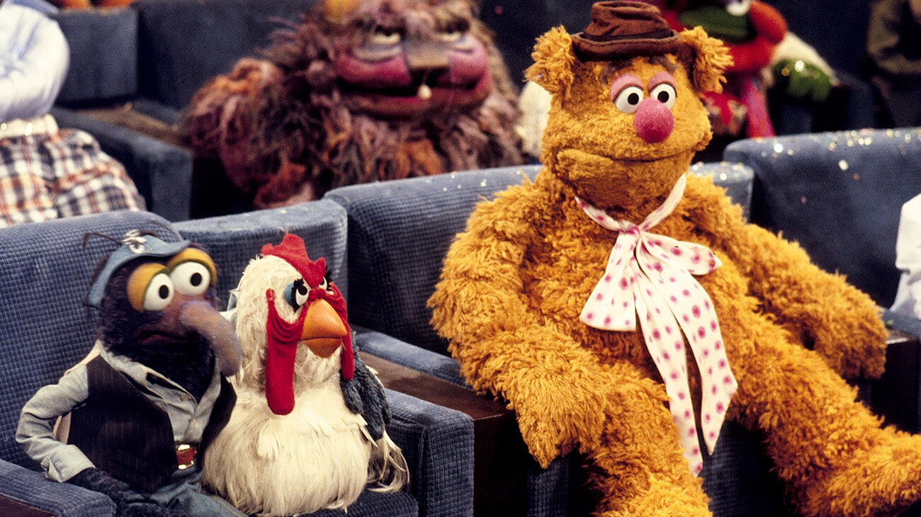 Camilla the chicken and Fozzie bear siting in a theater in The Muppet Movie