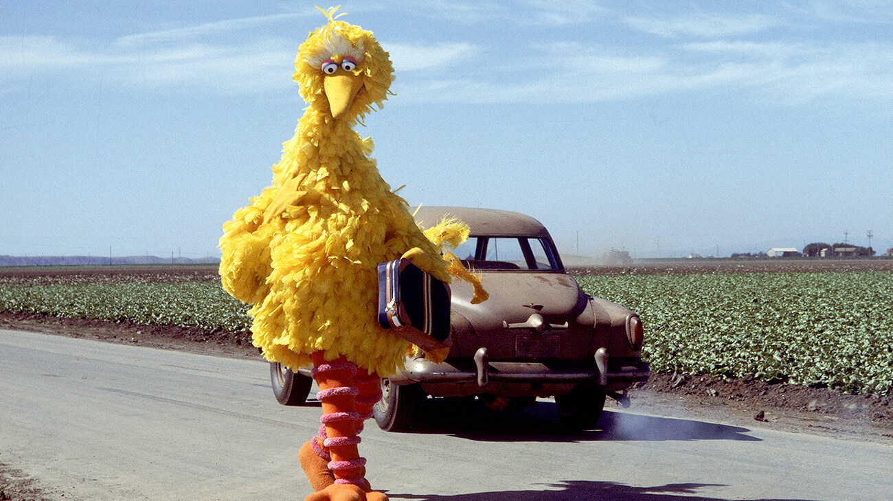 Big Bird walking for a road with a suitcase in The Muppet Movie