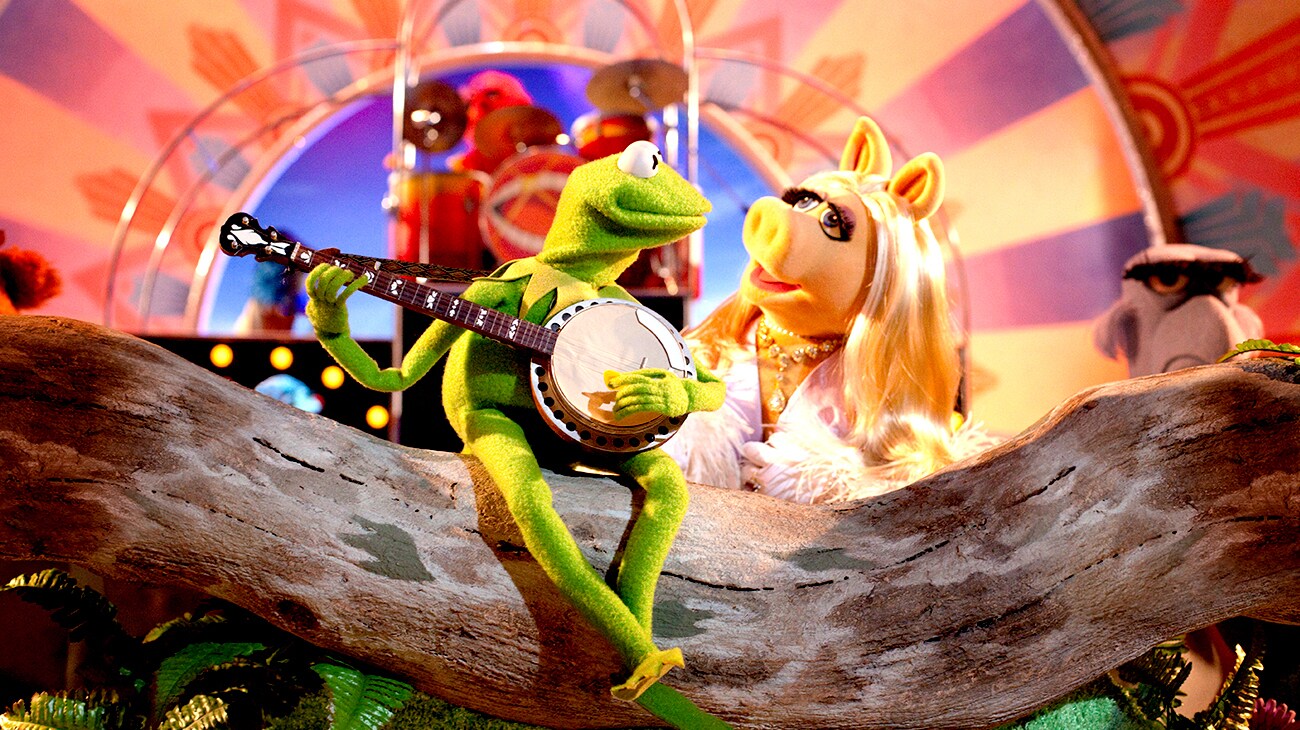 Miss Piggy listening to Kermit the Frog play a song with a banjo