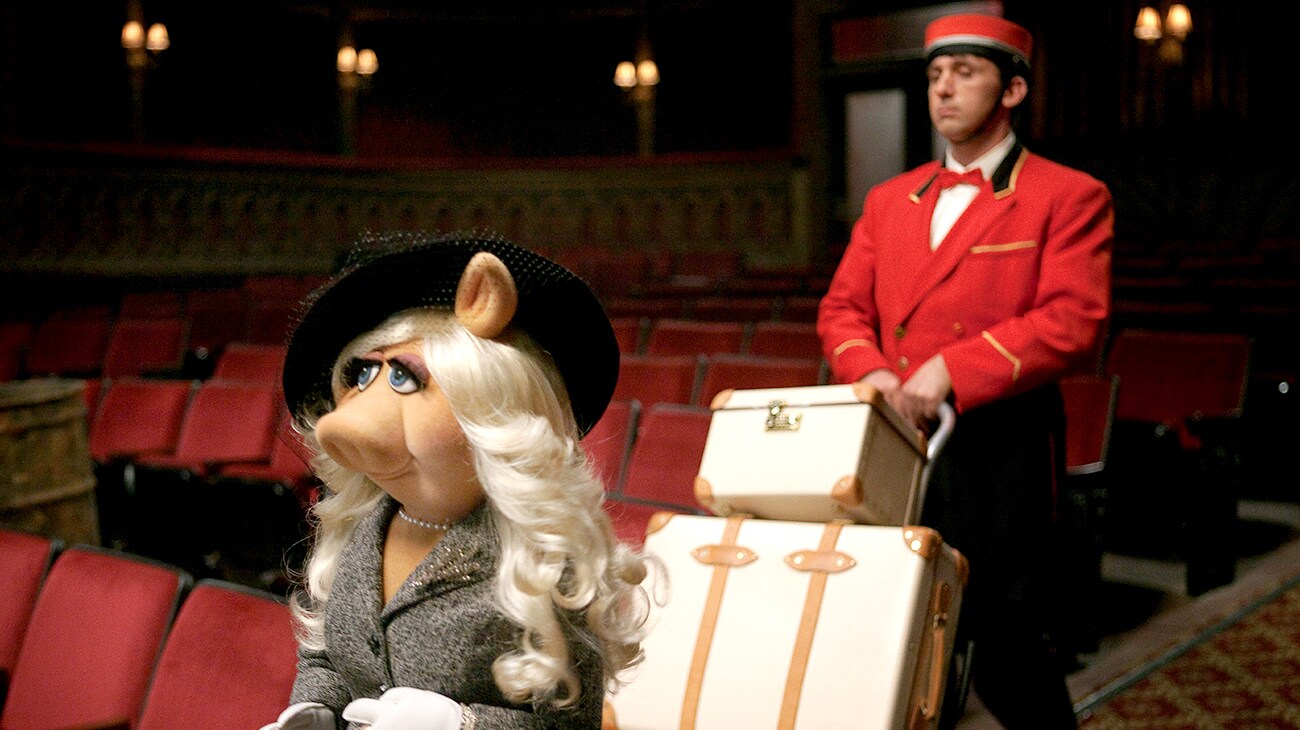 Miss Piggy arrives at the Muppet Theater with a bell boy carrying her luggage