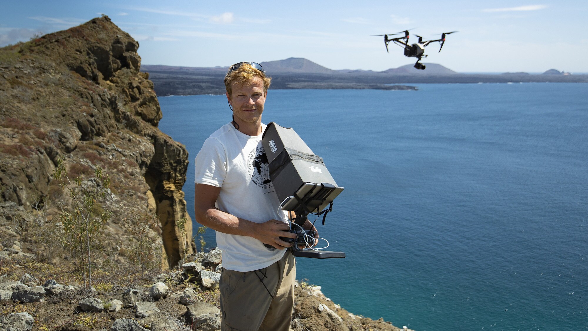 Bertie Gregory, holds the drone controls and monitor with the drone in the air to the side of him. (National Geographic for Disney+/Rakel Hansen)