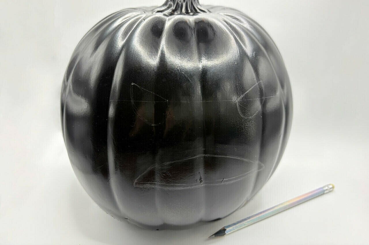 Begin by sketching the Amani’s half-circle eyes and mouth on the pumpkin.