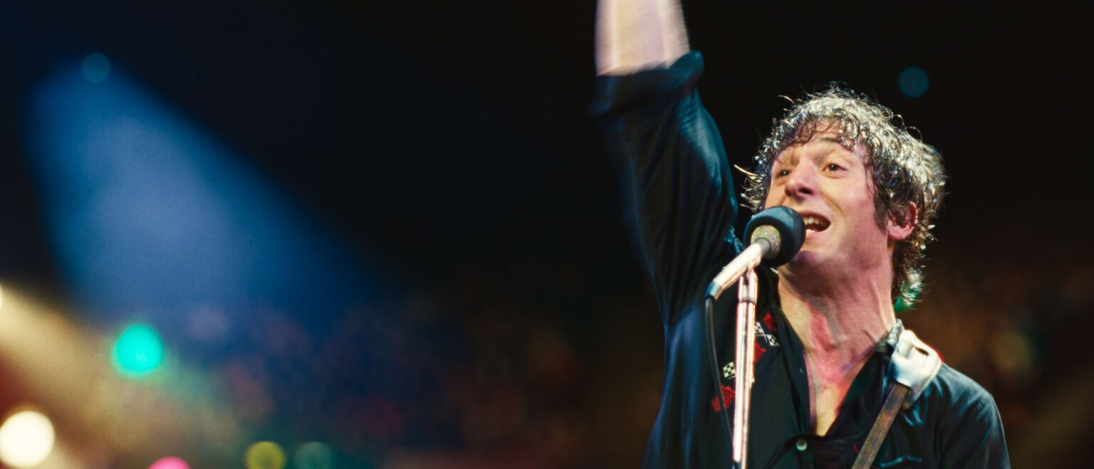 Bruce Springsteen (Jeremy Allen White) singing into a microphone at a concert. From the 20th Century Studios movie, "Springsteen: Deliver Me From Nowhere."