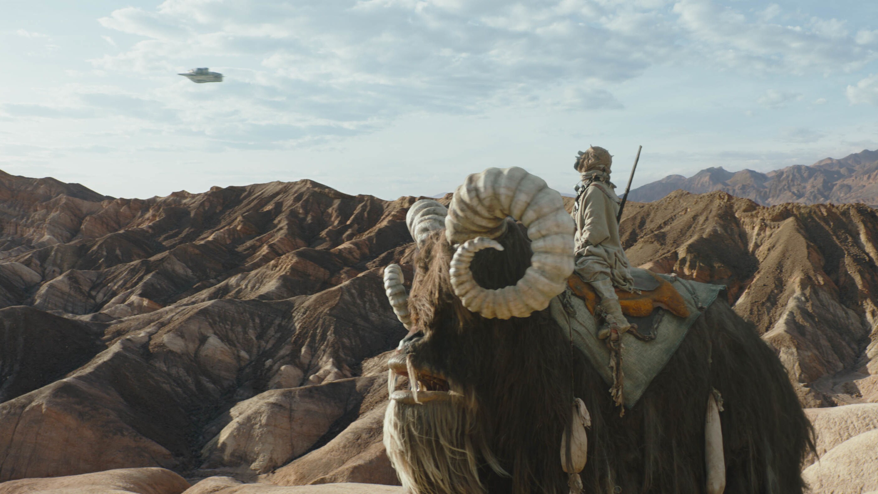 Tusken Raider rides on a bantha below with the Razor Crest in THE MANDALORIAN, season two. © 2020 Lucasfilm Ltd. & TM. All Rights Reserved.