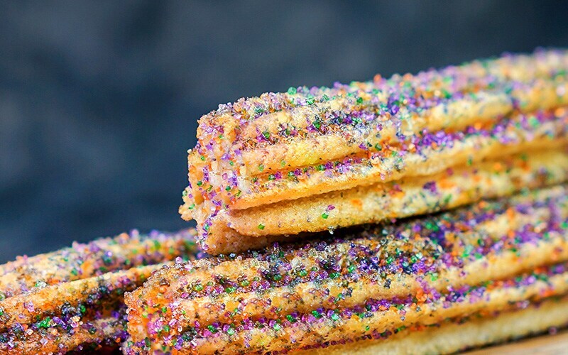Churros with purple green and orange sugar sprinkled on them