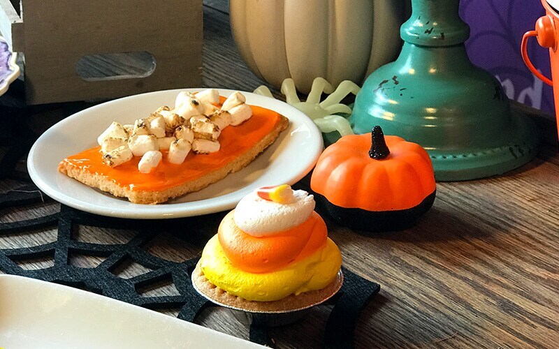 Plate of sweet potato hand pie next to a pumpkin desert and a white orange and yellow topped pie