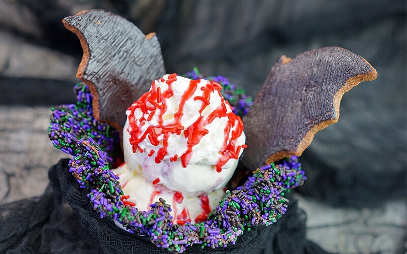 Halloween desert with cocolate covered bat wings and ice cream with red icing drizzled on top