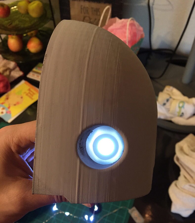 A brown, hard plastic material with what looks like a glowing blue eye at its center, used by a cosplayer in the creation of his life-size K-2SO costume.