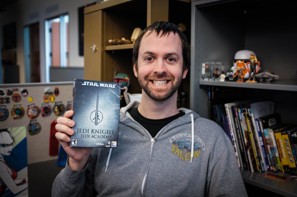 A member of the Lucasfilm Games Team holds up the box of Star Wars Jedi Knight: Jedi Academy.