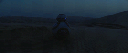 BB-8 rolls past a nightwatcher worm whose red eyes glow as they follow BB-8's movement through the nighttime desert of Planet Jakku.
