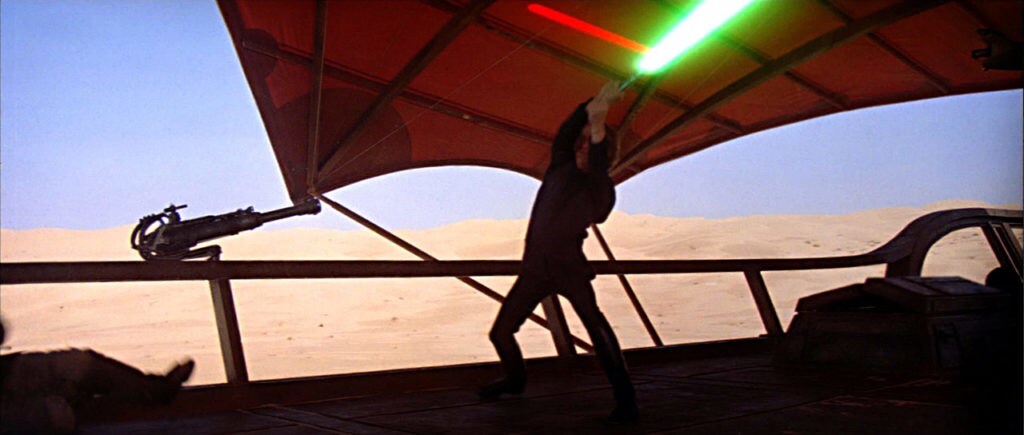 Luke Skywalker deflects laser fire with his lightsaber whle on Jabba's skiff in Return of the Jedi.