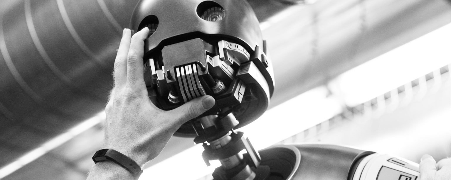 A hand adjusts the head of a life-size model of K-2SO created by Sideshow Collectibles.