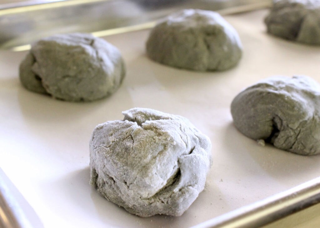 Balls of grey dough on a cookie sheet.