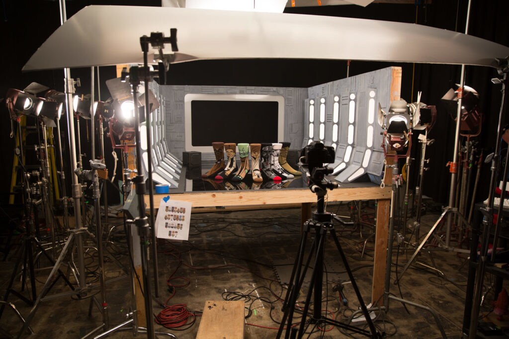 Star Wars socks by underwear company Stance are displayed on a miniature set with lighting and a camera focused on them for a photoshoot.