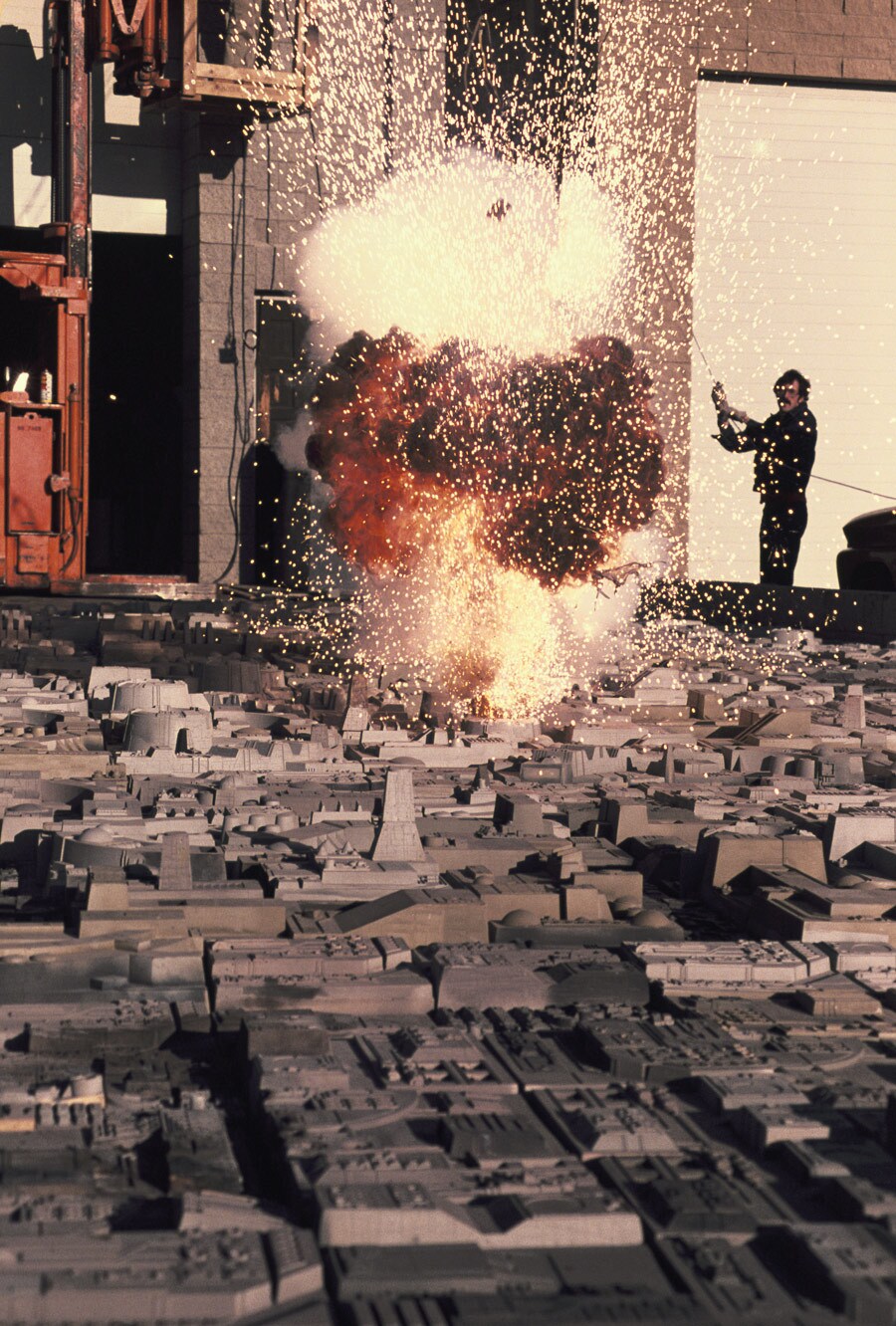 Model maker Paul Huston sets off an explosion on the surface of a model from Star Wars: A New Hope.