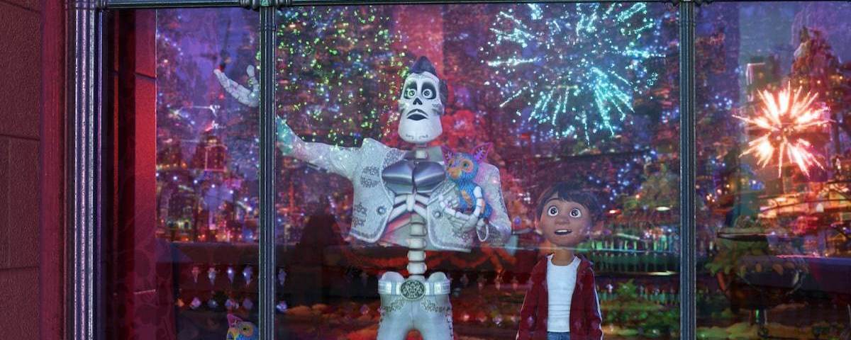 Ernesto de la Cruz and Miguel from Coco stand behind a window as fireworks erupt in the sky.