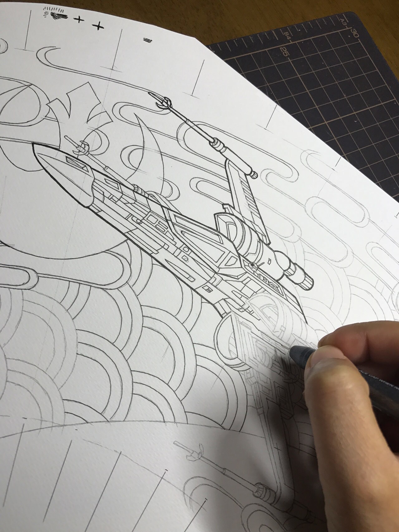 A pencil drawing of a starfighter being traced with an ink pen.