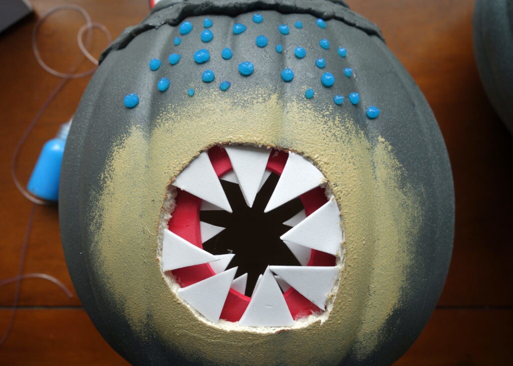A pumpkin carved and painted to look like a Summa-verminoth space monster.
