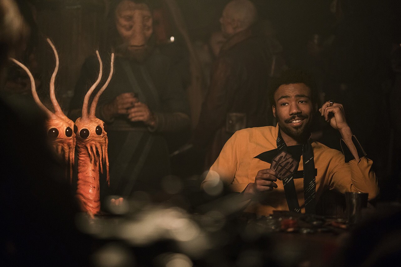 Lando Calrissian grins while holding holding his cards in Solo: A Star Wars Story.