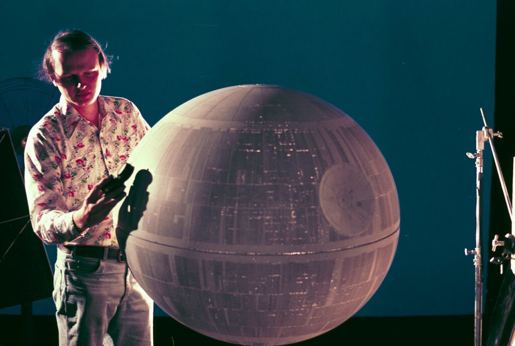 A visual effects artist checks the lighting around a model of the Death Star.