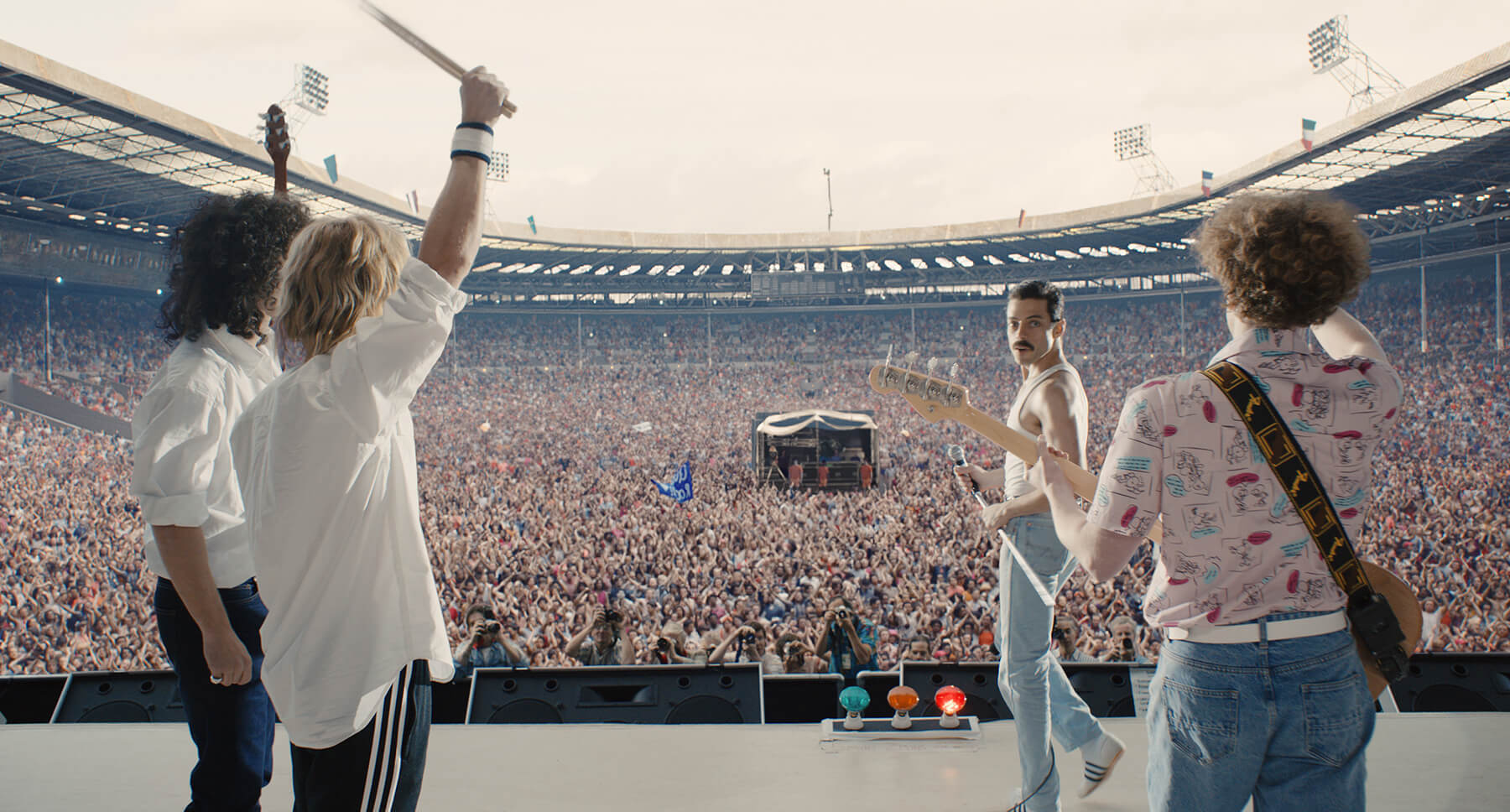 Actor Rami Malek (as Freddie Mercury) standing in front of a concert crowd in the movie "Bohemian Rhapsody"