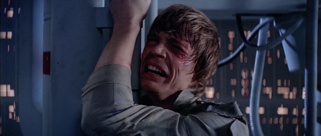 Luke Skywalker, battered and bloodied, clings to the catwalk within the Death Star in Star Wars: The Empire Strikes Back.