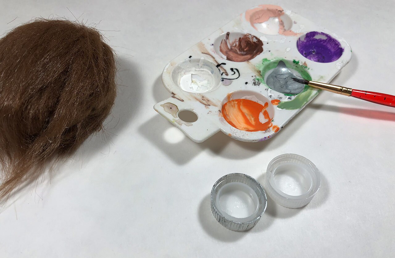 A stone covered with craft fur sits next to a tray of paints.