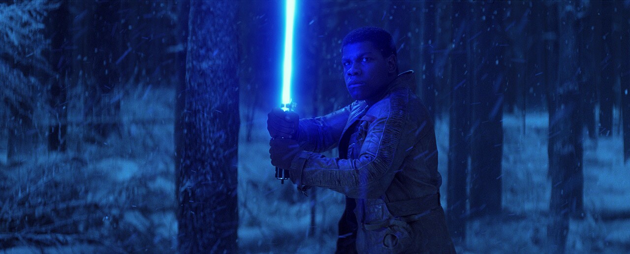 Finn brandishes a lightsaber in a snowy forest.