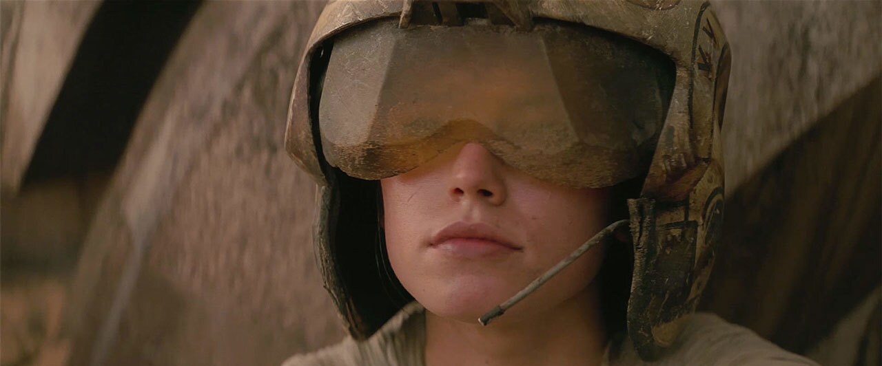 Rey wears a Rebel pilot helmet in The Force Awakens.