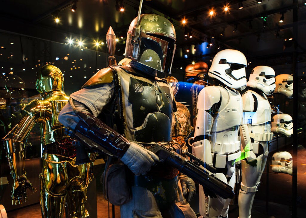 Boba Fett, a pair of stormtroopers, C-3PO, and several stormtrooper helmets are displayed in a glass case at the Star Wars Identities traveling exhibit.
