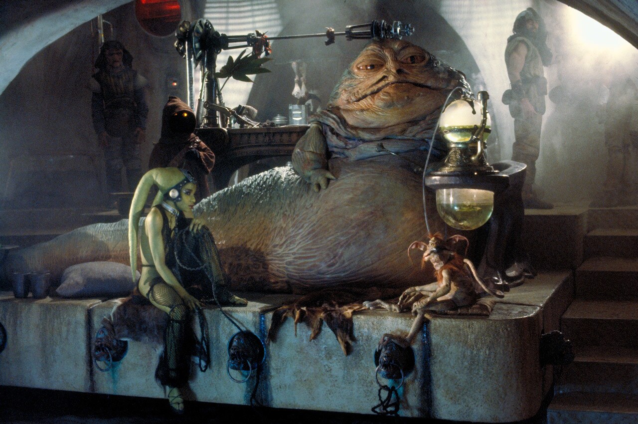 Jabba the Hutt sits on his throne alongside Salacious Crumb and a Twi'lek dancer in Return of the Jedi.