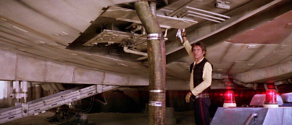 Han inspects the underside of the Millennium Falcon.