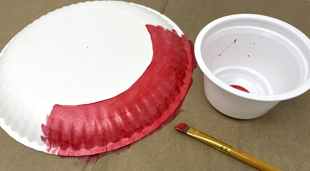 Step 6: Paint the outside edge of the paper plate with the hole with the red acrylic paint. Let dry.