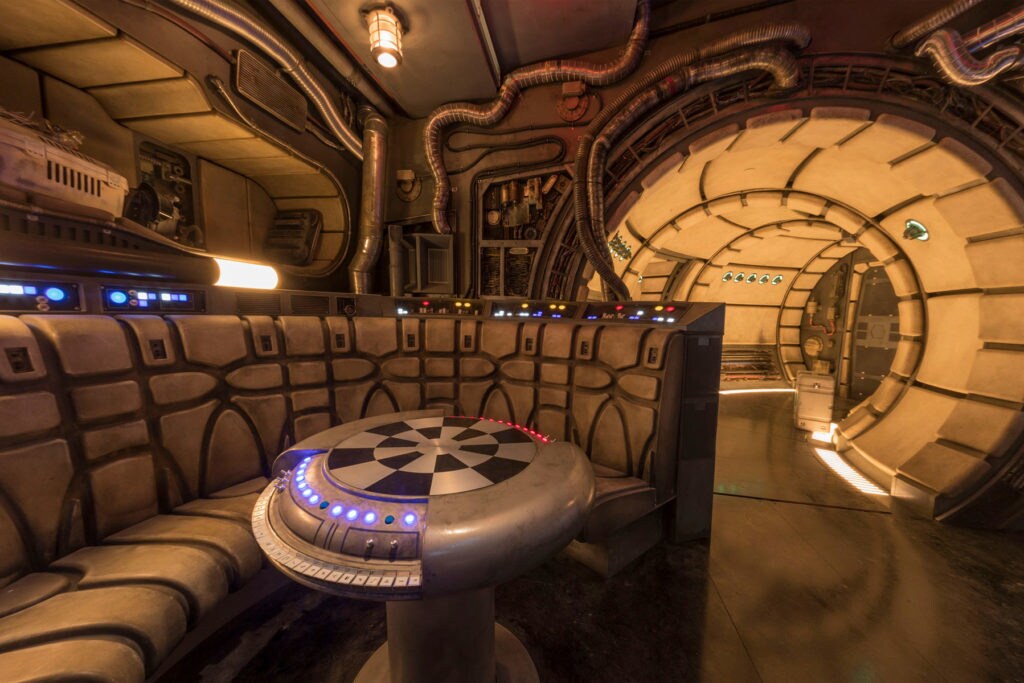 The lounge of the Millennium Falcon seen at Disney's Star Wars: Galaxy's Edge includes the hologame table and wrap-around bench.