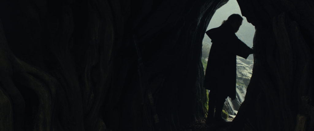 Luke Skywalker, in silhouette, stands in the entrance of a cave in The Last Jedi.