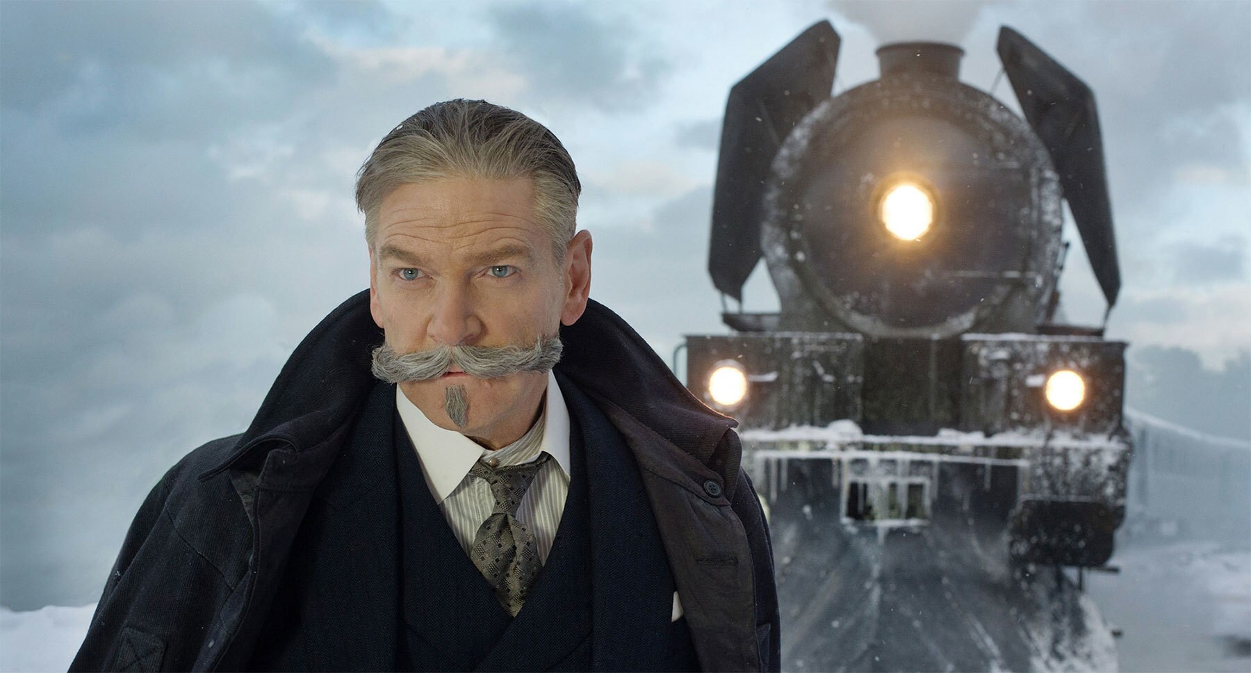Kenneth Branagh (as Hercule Poirot) standing next to a train in "Murder on the Orient Express"
