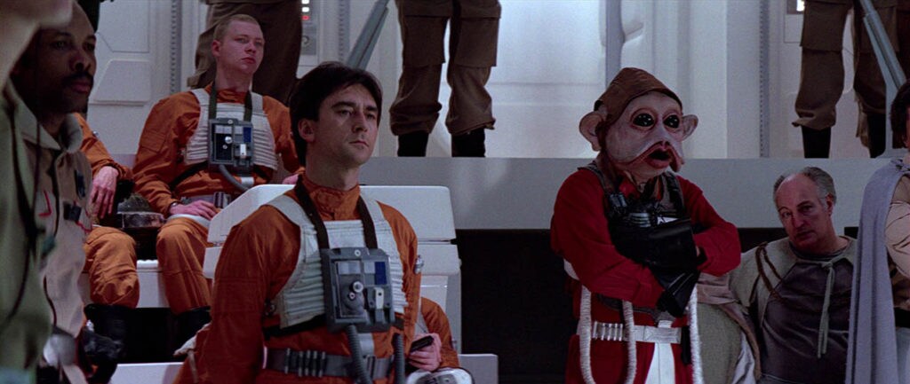 Wedge Antilles and other Rebel Alliance pilots listen to a mission briefing.