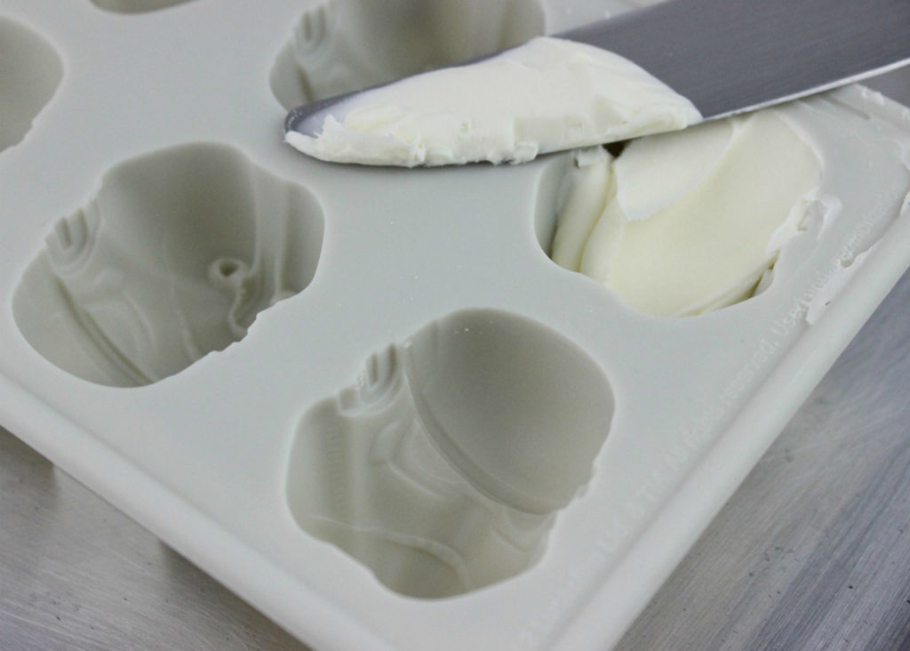Sour cream being pressed into silicon molds shaped like stormtrooper helmets.
