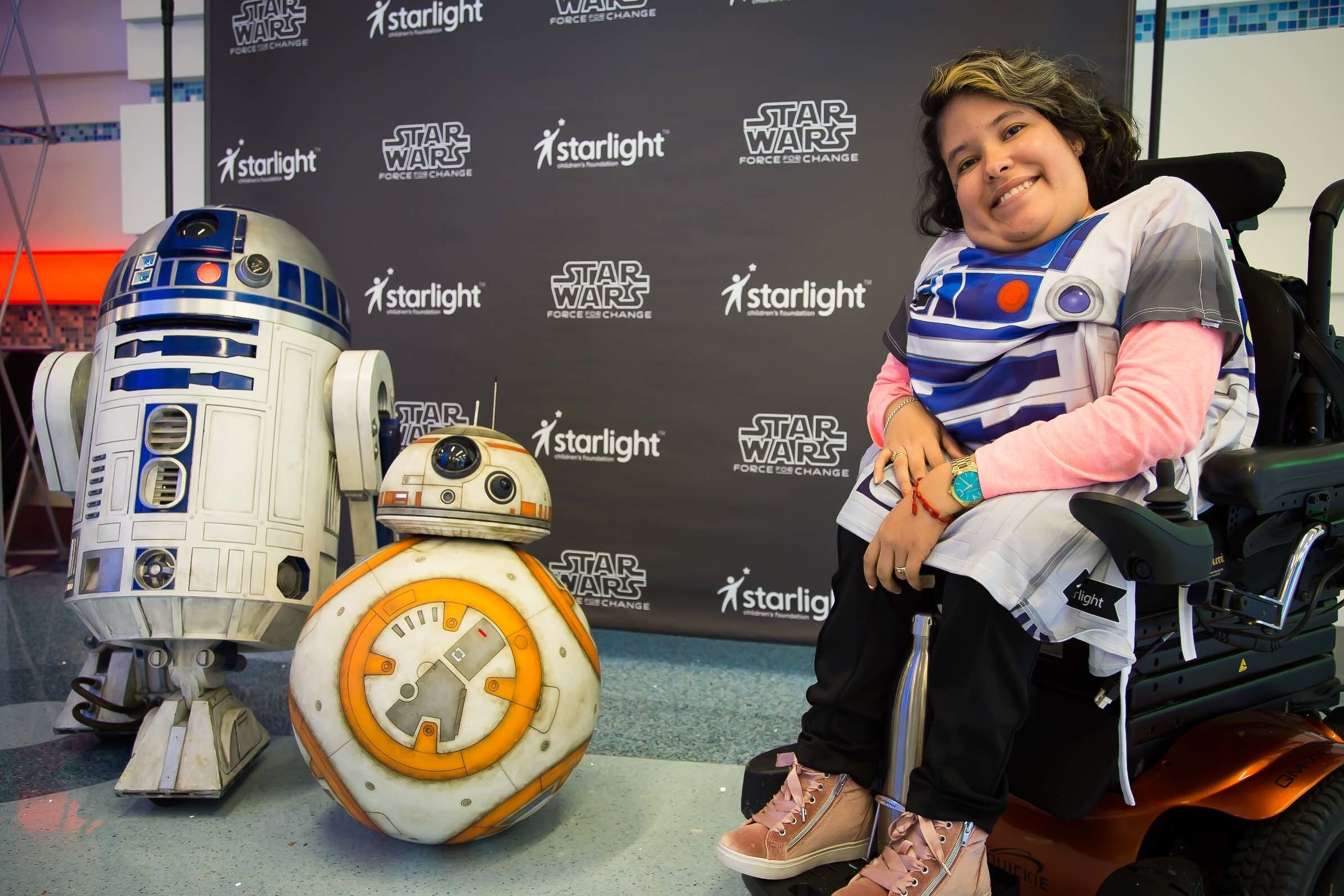 A child posing in their R2-D2 themed gown, alongside BB-8 and R2-D2